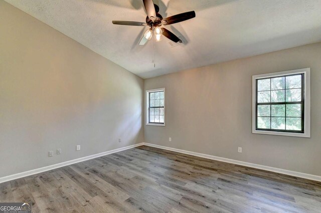 spare room with lofted ceiling, ceiling fan, wood-type flooring, and a textured ceiling