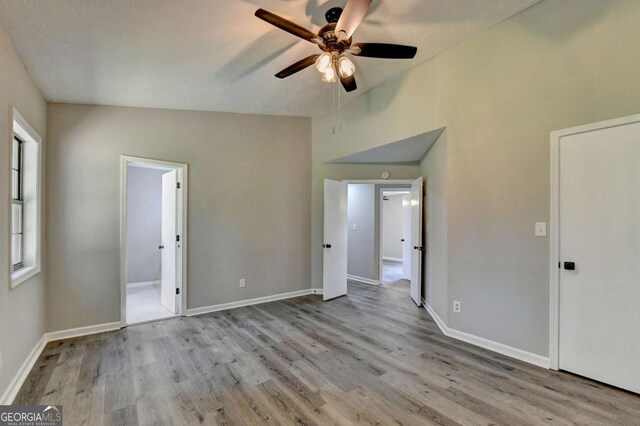 unfurnished bedroom with ceiling fan, lofted ceiling, and light hardwood / wood-style flooring