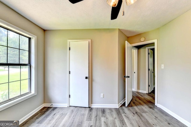 unfurnished bedroom with ceiling fan, light hardwood / wood-style flooring, and a textured ceiling