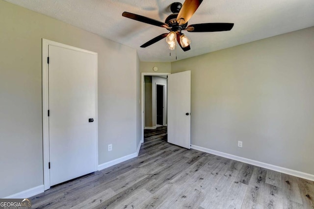 unfurnished bedroom with a textured ceiling, light hardwood / wood-style floors, and ceiling fan