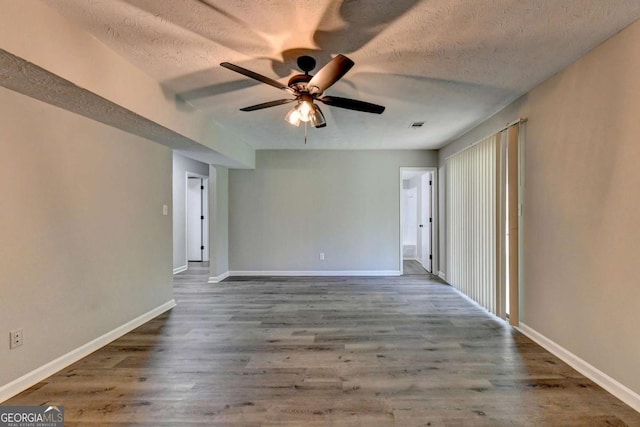 unfurnished room with ceiling fan, dark hardwood / wood-style flooring, and a textured ceiling