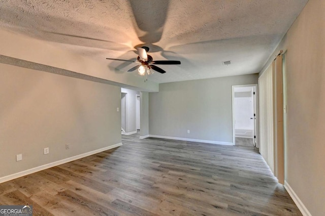 spare room with hardwood / wood-style flooring, ceiling fan, and a textured ceiling