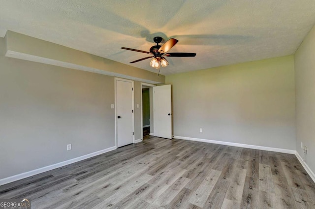 unfurnished room featuring ceiling fan, light hardwood / wood-style floors, and a textured ceiling