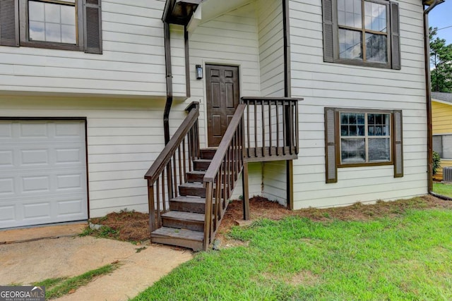 view of exterior entry featuring a garage and a lawn