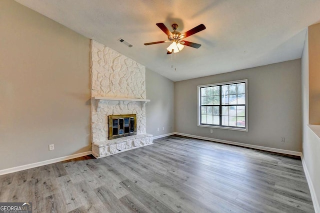 unfurnished living room featuring a textured ceiling, ceiling fan, a fireplace, light hardwood / wood-style floors, and lofted ceiling