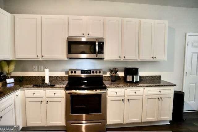 kitchen with white cabinets, stainless steel appliances, and dark stone countertops