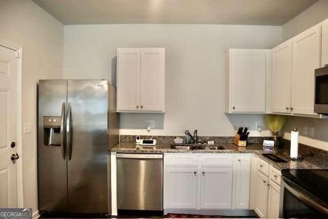 kitchen featuring dark stone countertops, white cabinetry, sink, and appliances with stainless steel finishes