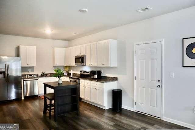 kitchen with dark hardwood / wood-style floors, a kitchen island, white cabinetry, and stainless steel appliances