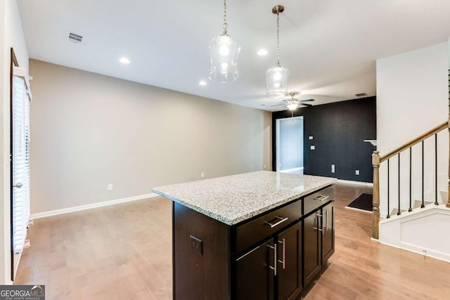 kitchen featuring ceiling fan, a center island, hanging light fixtures, light hardwood / wood-style floors, and dark brown cabinets