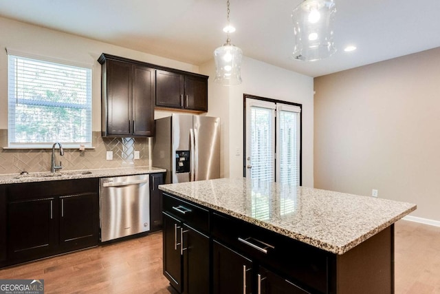 kitchen featuring tasteful backsplash, stainless steel appliances, sink, pendant lighting, and a center island