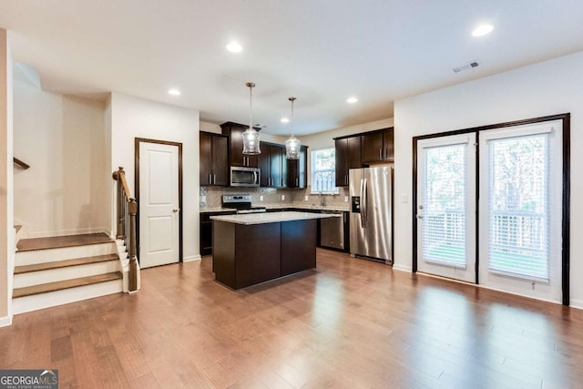 kitchen featuring pendant lighting, dark brown cabinetry, stainless steel appliances, and a kitchen island