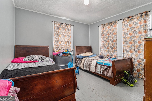 bedroom with wood-type flooring, a textured ceiling, and ornamental molding