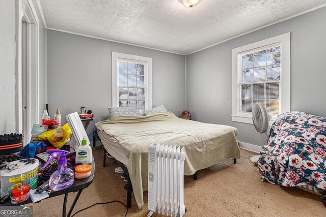 carpeted bedroom with radiator heating unit, a textured ceiling, and crown molding