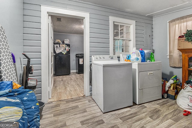 laundry area with wood walls, light hardwood / wood-style floors, and independent washer and dryer