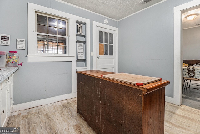 interior space with a textured ceiling, light hardwood / wood-style floors, and ornamental molding