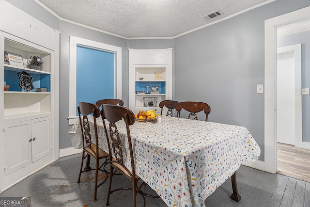 dining room with a textured ceiling, dark hardwood / wood-style floors, built in features, and ornamental molding