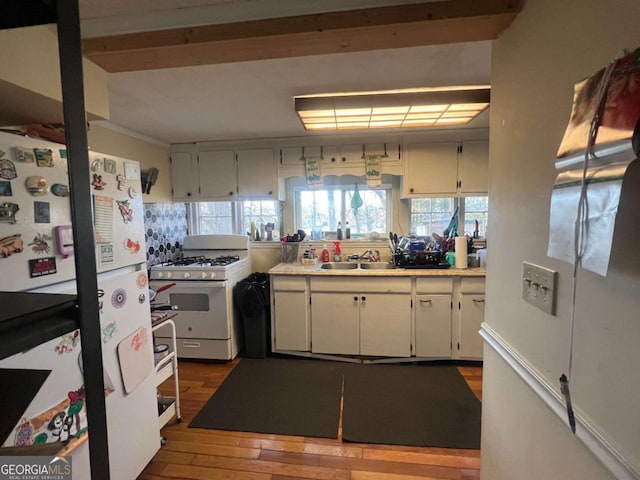 kitchen with white cabinetry, sink, dark hardwood / wood-style floors, and white appliances