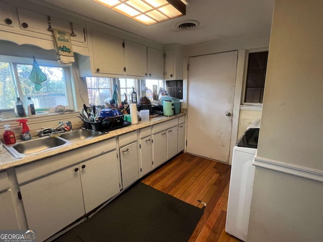 kitchen with white cabinets, dark hardwood / wood-style flooring, sink, and washer / clothes dryer