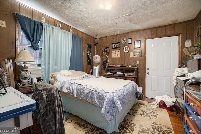 bedroom with a textured ceiling, wood walls, and light hardwood / wood-style floors