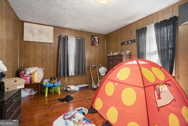 bedroom with wood walls, wood-type flooring, and a textured ceiling