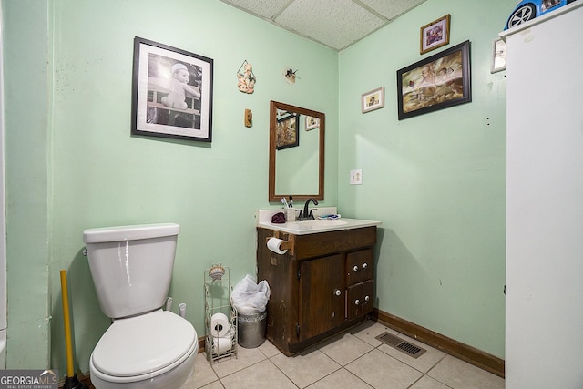 bathroom featuring a paneled ceiling, toilet, vanity, and tile patterned floors