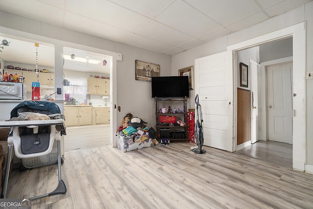 living room featuring a drop ceiling and light hardwood / wood-style floors