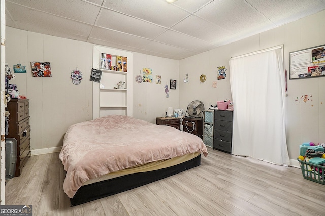 bedroom featuring wood-type flooring and a drop ceiling