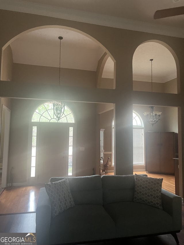 living room featuring a notable chandelier, plenty of natural light, wood-type flooring, and ornamental molding