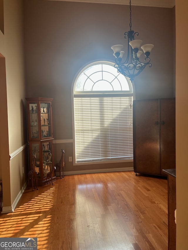 unfurnished dining area with wood-type flooring and an inviting chandelier