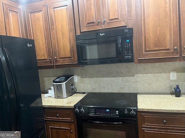 kitchen featuring tasteful backsplash, light stone countertops, dark brown cabinets, and black appliances