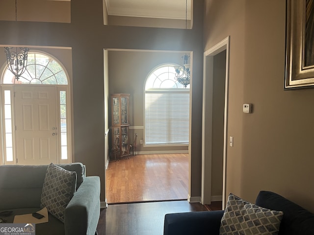 foyer with dark hardwood / wood-style flooring, ornamental molding, and a chandelier