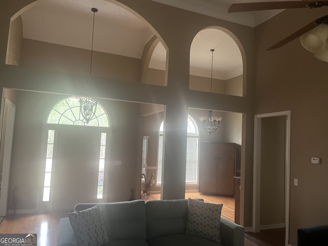 living room with a towering ceiling, light hardwood / wood-style floors, and an inviting chandelier