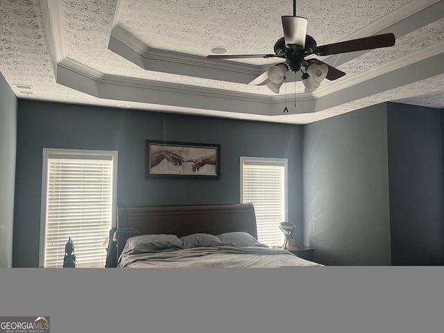 bedroom with ceiling fan, ornamental molding, and a tray ceiling