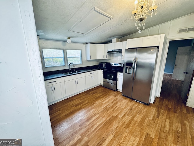 kitchen with appliances with stainless steel finishes, sink, white cabinets, hardwood / wood-style floors, and lofted ceiling