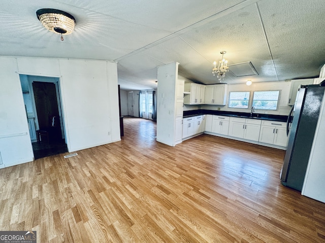 kitchen featuring white cabinets, stainless steel refrigerator, plenty of natural light, and sink