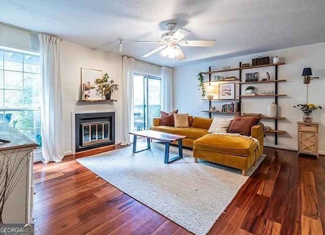 living room with a textured ceiling, dark hardwood / wood-style floors, and ceiling fan