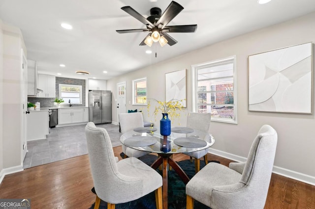 dining space featuring ceiling fan, sink, and dark wood-type flooring