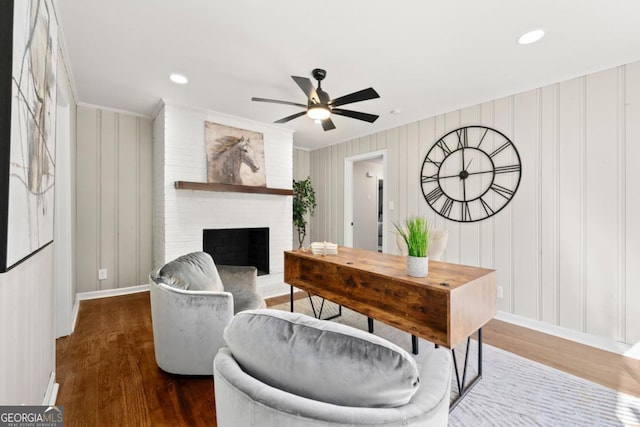 living room featuring dark hardwood / wood-style floors, a brick fireplace, ceiling fan, and ornamental molding