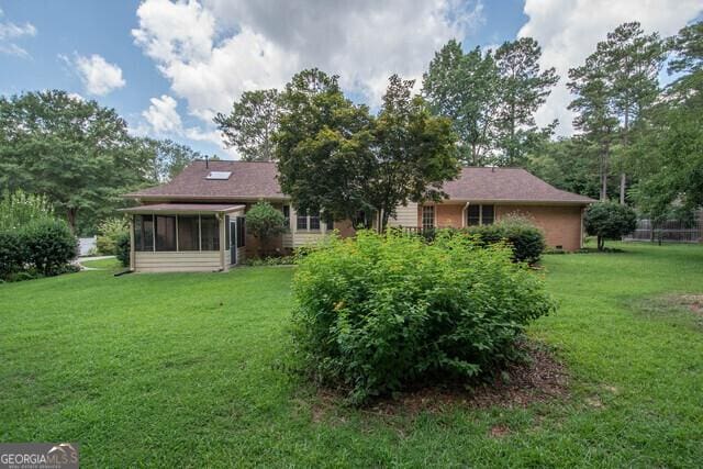 back of property with a lawn and a sunroom