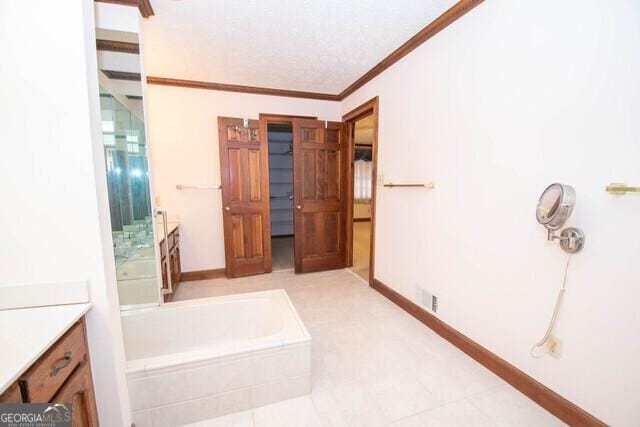 bathroom featuring vanity, ornamental molding, and tiled bath