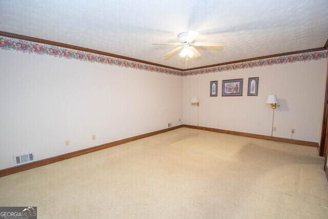 empty room with ceiling fan, carpet floors, and a textured ceiling