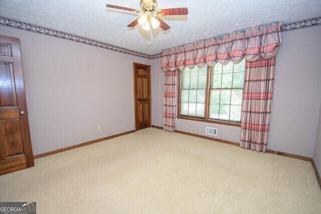 unfurnished room featuring ceiling fan, light carpet, and a textured ceiling