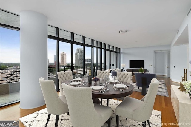 dining area with plenty of natural light, floor to ceiling windows, and light hardwood / wood-style floors