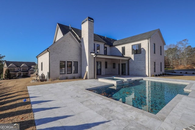 rear view of property with a patio and a pool with hot tub