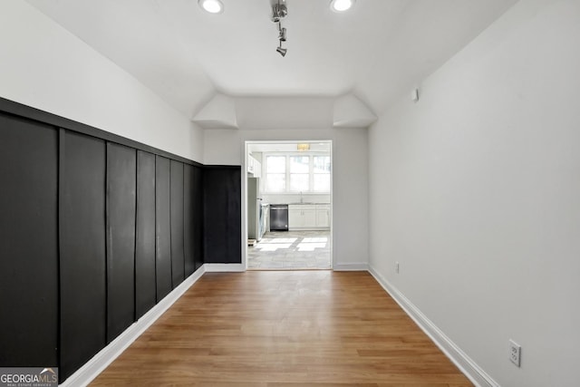 hall featuring sink, light hardwood / wood-style floors, and vaulted ceiling