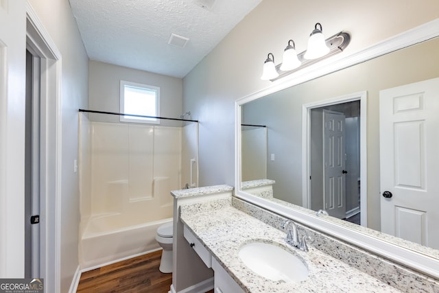 full bathroom featuring tub / shower combination, vanity, a textured ceiling, wood-type flooring, and toilet