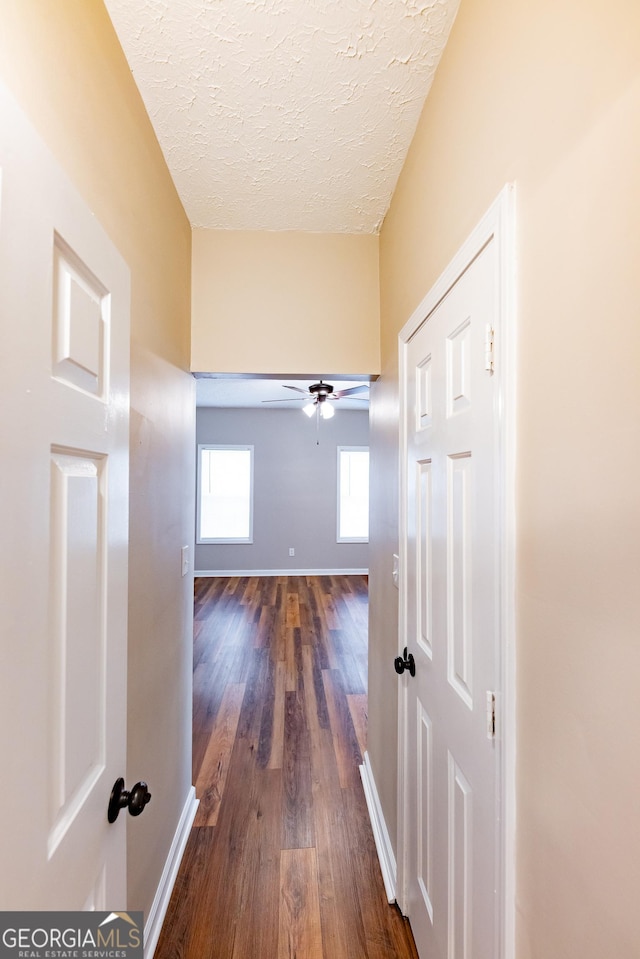 hallway featuring dark hardwood / wood-style flooring and a textured ceiling