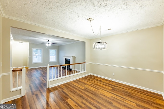 spare room featuring ceiling fan, dark wood-type flooring, a textured ceiling, and ornamental molding