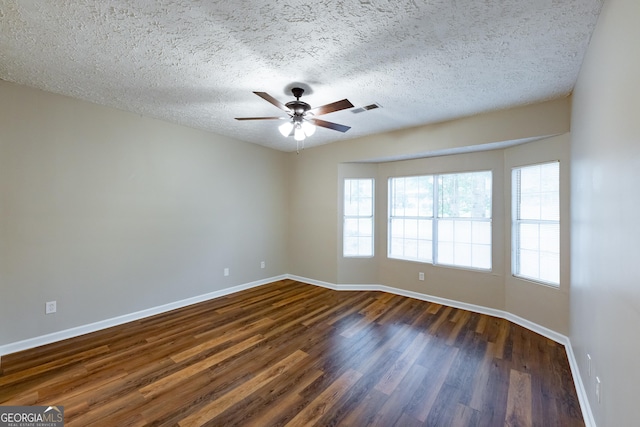 empty room with ceiling fan, dark hardwood / wood-style flooring, and a textured ceiling