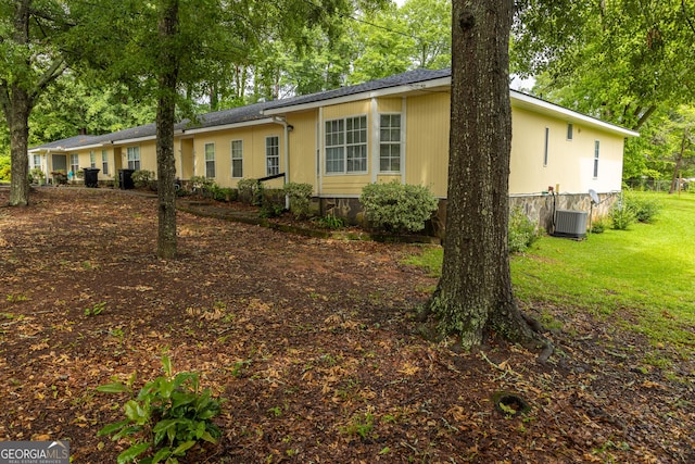 ranch-style house with central air condition unit and a front lawn